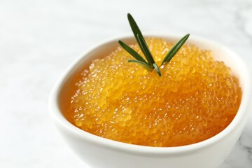 Fresh pike caviar and rosemary in bowl on white table, closeup