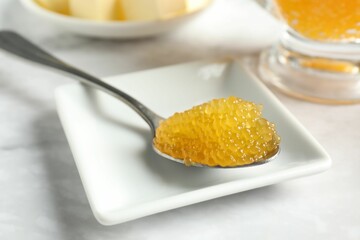 Fresh pike caviar in spoon on white marble table, closeup