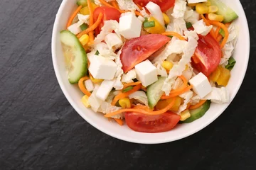 Poster Tasty salad with Chinese cabbage, carrot, cheese, cucumber, corn and tomato on black table, top view © New Africa