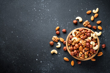 Nuts assortment at black background. Almond, hazelnut, cashew in wooden bowl. Flat lay with copy space. - 783200314