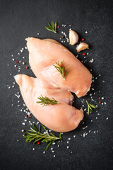 Chicken meat. Raw chicken breast with herb and spices at black background. Top view, vertical. - 783202553