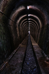 Fototapeta na wymiar long tunnel, illuminated by artificial lights, surrounded by walls on either side, water channel