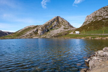 Fototapeta na wymiar A body of water, the Lakes of Covadonga, is nestled amidst towering mountains, the Picos de Europa. The serene lake reflects the majestic mountains in the background.