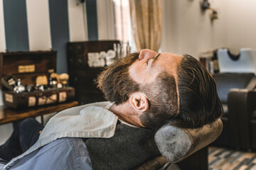 Leisurely moment at upscale barber shop. A client enjoys the serene ambiance, reflecting on quality grooming time.