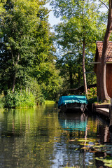 Scenic view green riverside garden house moored boat  german national biosphere reserve park Spreewald spring summer sunny day. Spree river forest greenery canal nature tranquil landscape in Germany