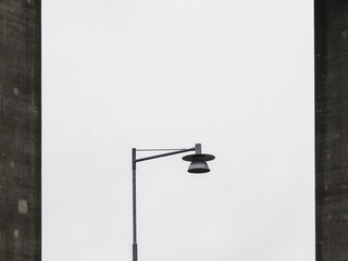 A street light stands next to a towering building in an urban setting. The contrast between the...