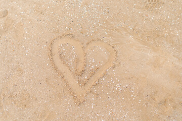 An intricately drawn heart shape stands out on the sandy beach, encapsulating the timeless allure...