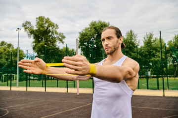 Athletic man holding a yellow resistance band on a court outside