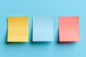 Fototapeta premium Three Different Colored Sticky Notes on a Blue Background