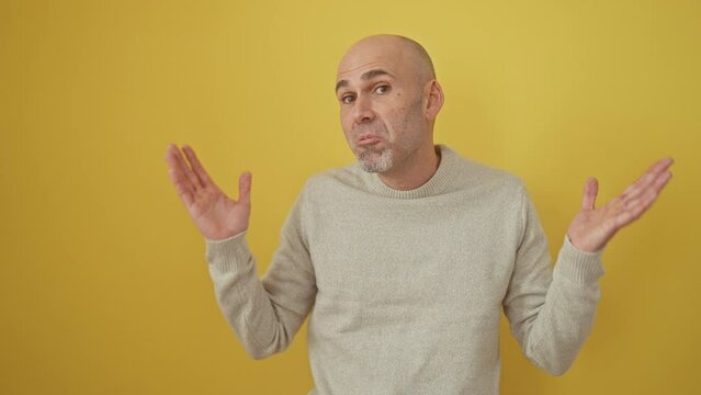Crazy, furious bald man, hispanic with beard, sporting a yellow sweater, yelling his lungs out! communication in full rage, ear-splitting to the side, hand cupping his mouth - isolated background.