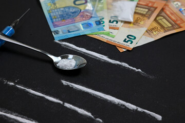 cocaine lines with syringe and spoon, bag full of heroin on black background and pile of euro...