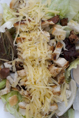 Caesar salad. Top view of fresh a salad with lettuce, parmesan cheese, bread croutons, sliced grilled chicken breast and bacon	