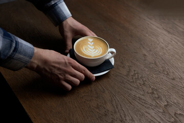 Waiter Serving a Perfectly Crafted Latte With Artful Foam Design on a Wooden Table in coffee shop
