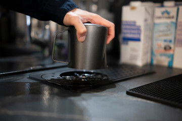 Mans Hand Holding a Metal Cup Over an Automatic Washer at a Bar Counter During Nighttime
