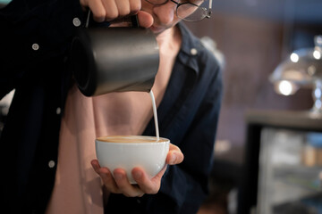 Barista Pouring Steamed Milk Into a cappuccino  Coffee Cup at a Local Cafe