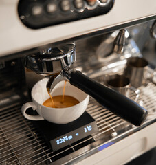 Espresso pouring in white cup close up, Preparation at a Modern Coffee Machine Showing Time and Weight