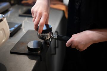 Fototapeta na wymiar Barista Preparing Espresso With a Tamper in Coffee Shop Kitchen During Morning Rush