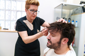 Hairdresser carefully perfects the fit and look of a hairpiece.