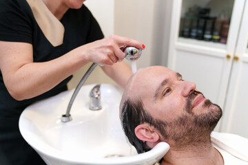 Technician washing client's hair before prosthesis application.