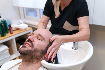 Man enjoys a gentle scalp wash at a hair clinic.