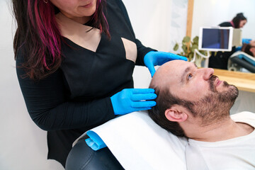 Clinician analyzes patient's scalp before a hair restoration process.