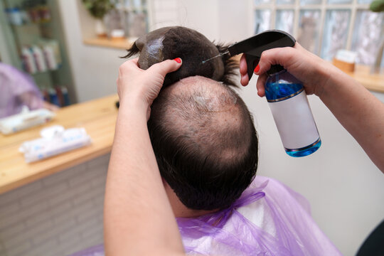 Stylist detaches a hairpiece, starting the maintenance routine.