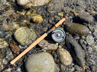 Fly fishing rod and reel on flowing river bed - 783247773