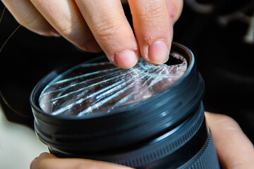 Photographer removing broken pieces of glass out of DSLR photo camera lens filter after if fall...