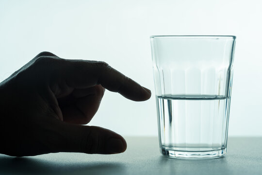 A glass half full of water concept, with a hand showing the part of a half of water, positive mindset, and point of view.