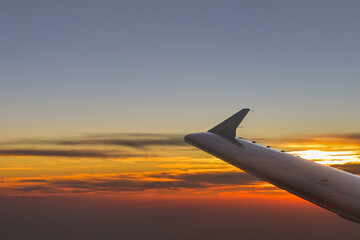 Wing of a passenger jet silhouetted against a sunset sky