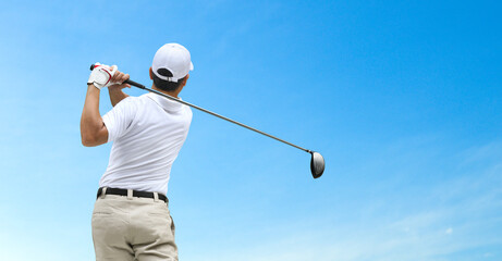 Golfer hit sweeping driver after hitting golf ball with blue sky background.