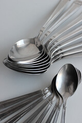 Eight tablespoons and eight teaspoons laid out in a fan shape isolated on white surface
