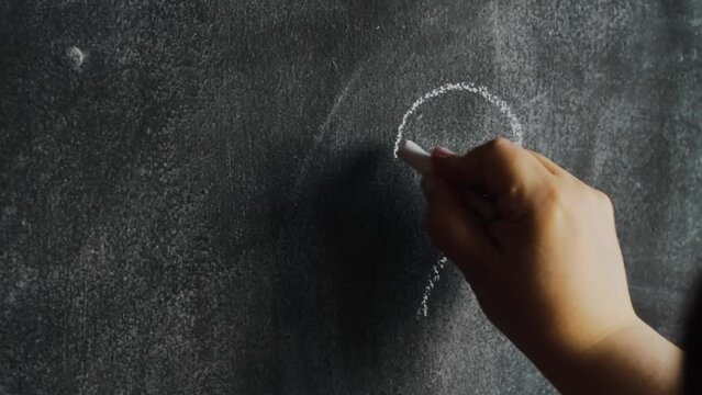 A hand drawing heart with chalk on chalkboard and cleaning it