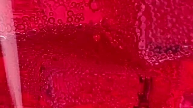 Close up pouring soft Drinks, red soda with ice into Glass Isolated