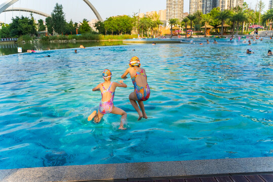 two Asian kids jumpping in the swimming pool