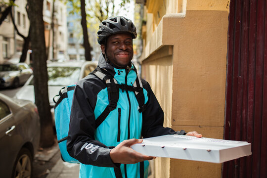 Happy delivery man with a pizza box on a city street