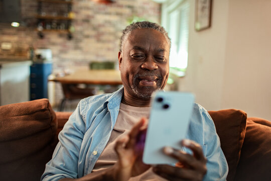 Senior black man using smartphone on the couch