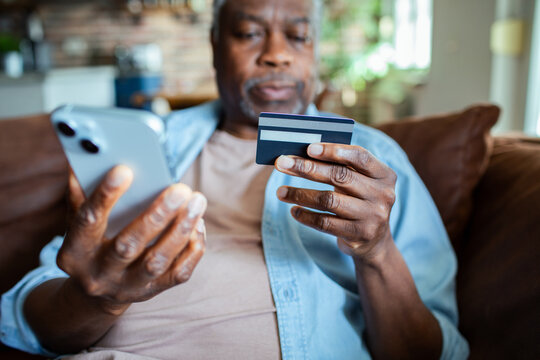 Senior man online shopping with credit card and smartphone at home