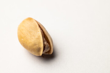 One pistachio nut on a white background, close-up