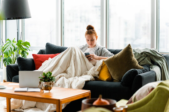 A woman uses a mobile phone and laptop at home