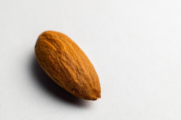Almonds on a white background, close-up of the seed from the side. One nut macro shot