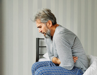 senior bed man problem pain headache home elderly mature pain bedroom upset caucasian adult...
