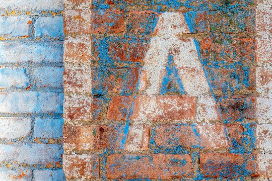 old colorful painted brick wall with large letter A stenciled on