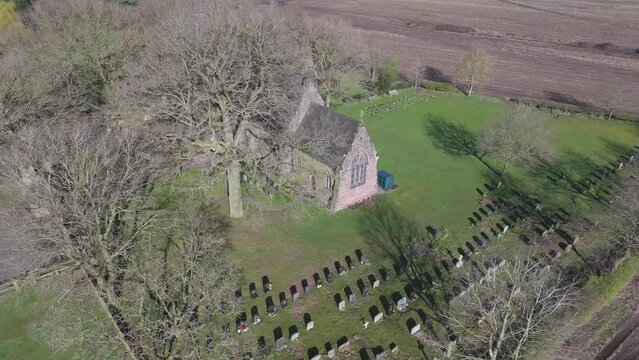Aerial shot of St John the Evangelist's Church and church cemetery in Toft, Cheshire, England, UK
