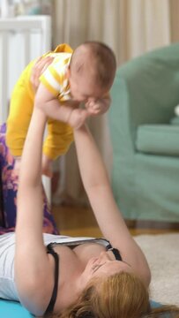 Young fit mother doing fitness exercises together with her baby in the nursery. A set of exercises for a young mother in the postpartum. Sport, motherhood, postpartum and active lifestyle.