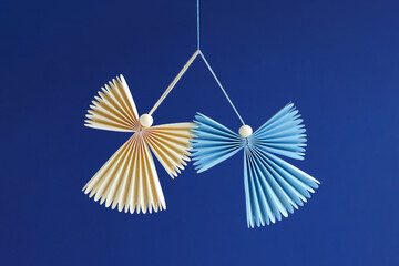 Origami angels with wings and strings for hanging in blue studio