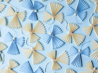 Multiple cute origami angel figures placed on plain blue background