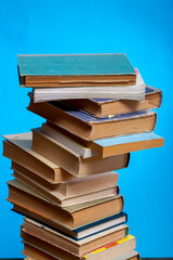 A stack of old books and notebooks on the table on a blue background