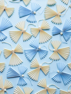 Creative handmade origami figures of angels laying on blue background