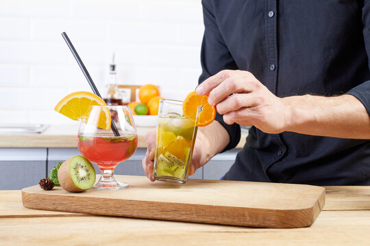 Mixologist preparing alcoholic drink in the glass at home. Female bartender hand making cocktail. Barman cooking fresh cold beverage with spoon in glass with ice.